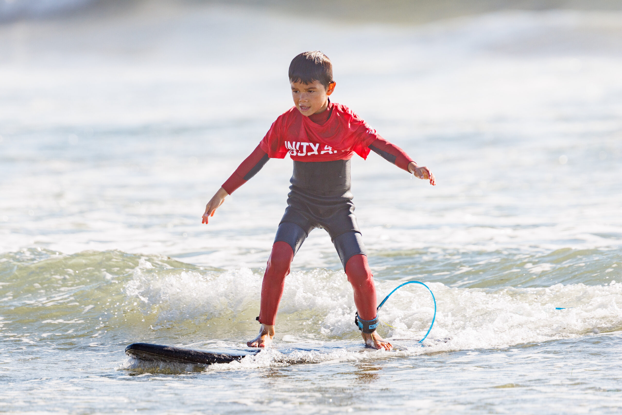 A young volunteer surfing at San Diego charity Unity 4 Orphans' Wave-a-Thon