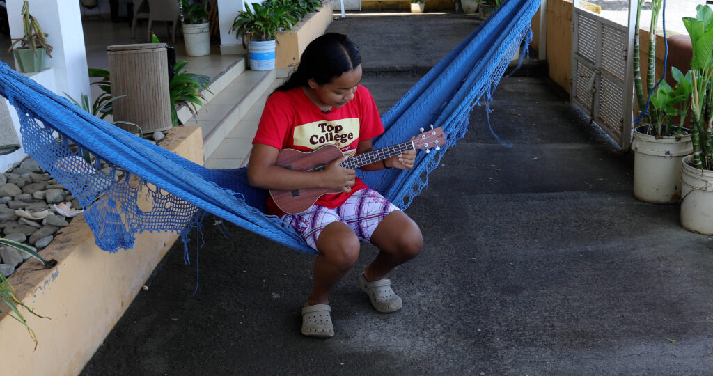Nicaraguan student playing the guitar sitting in a hammock