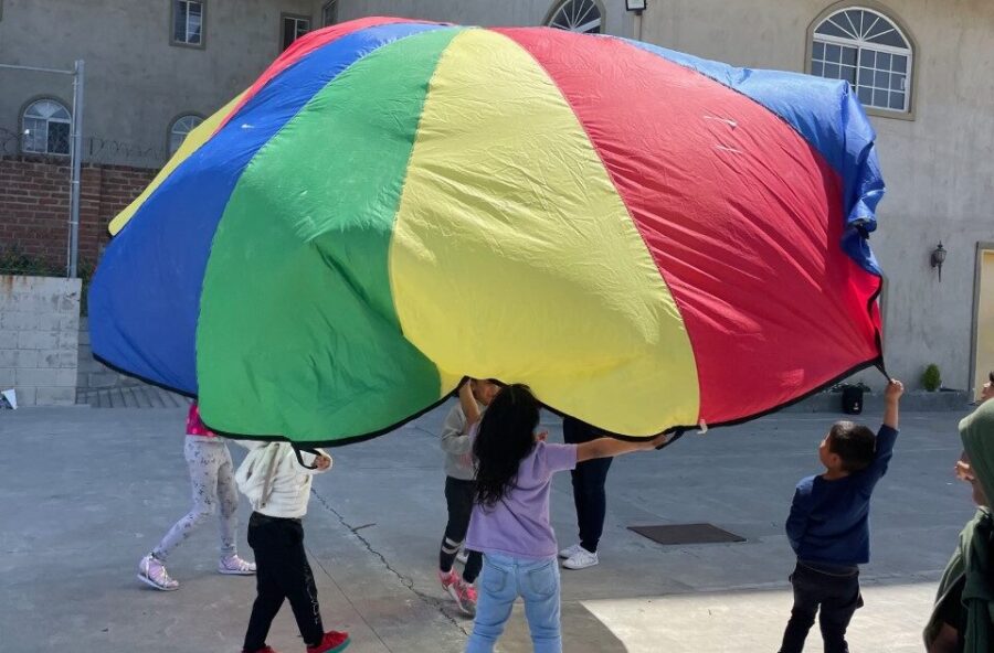 children and Unity 4 Orphans volunteers at an orphanage in Mexico playing with a rainbow parachute