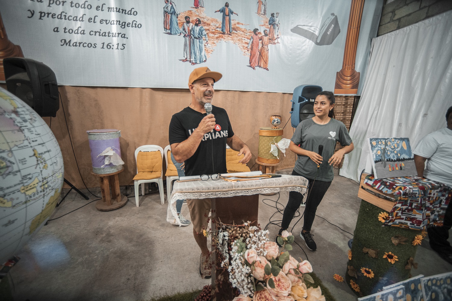 A man and a woman stand in front of a podium with microphones in their hands at the Ecuador charity event. They are both smiling, proud of their work with the non-profit organization U4O.