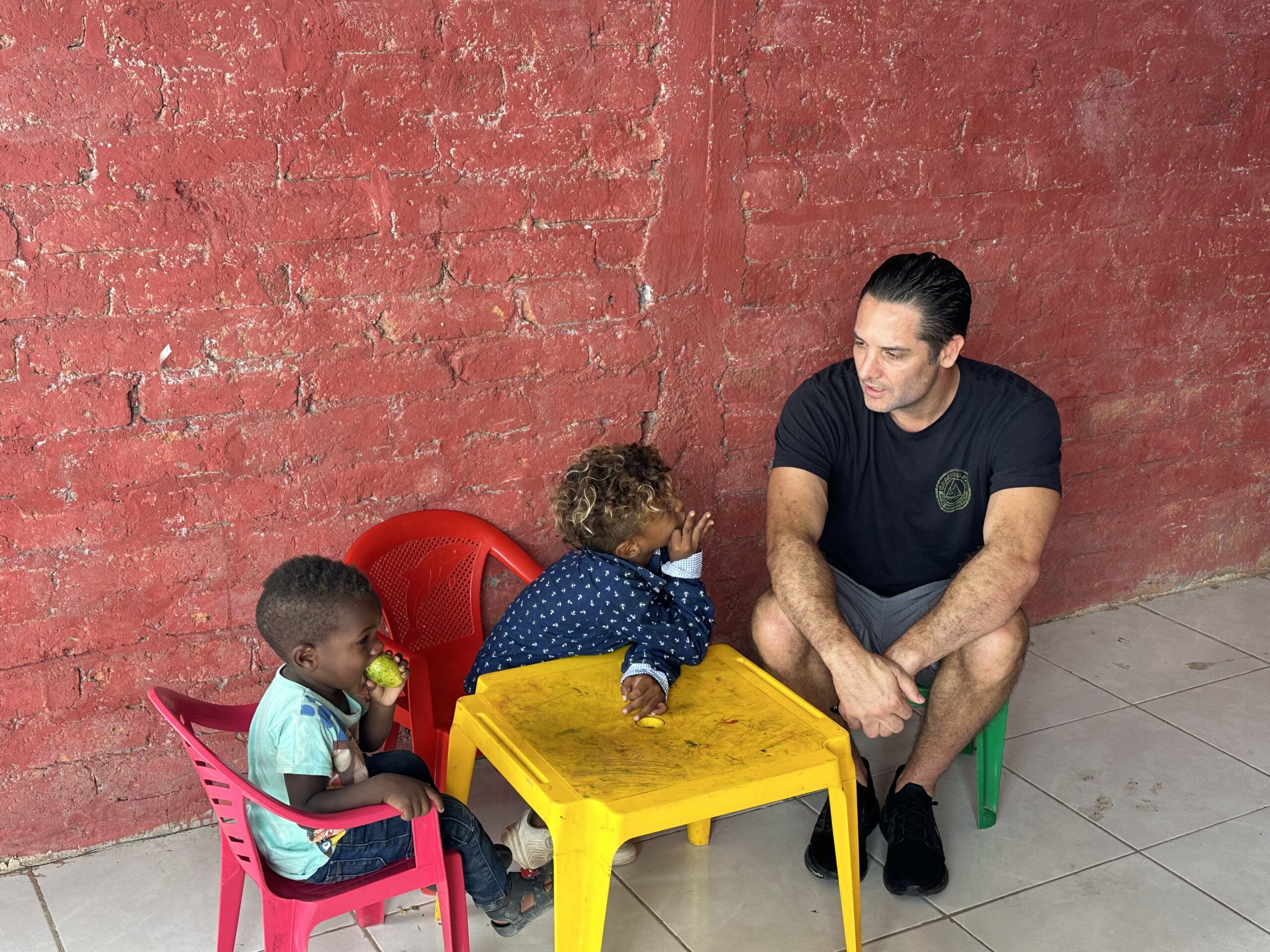 A U4O team member sits at a child's table with children in need
