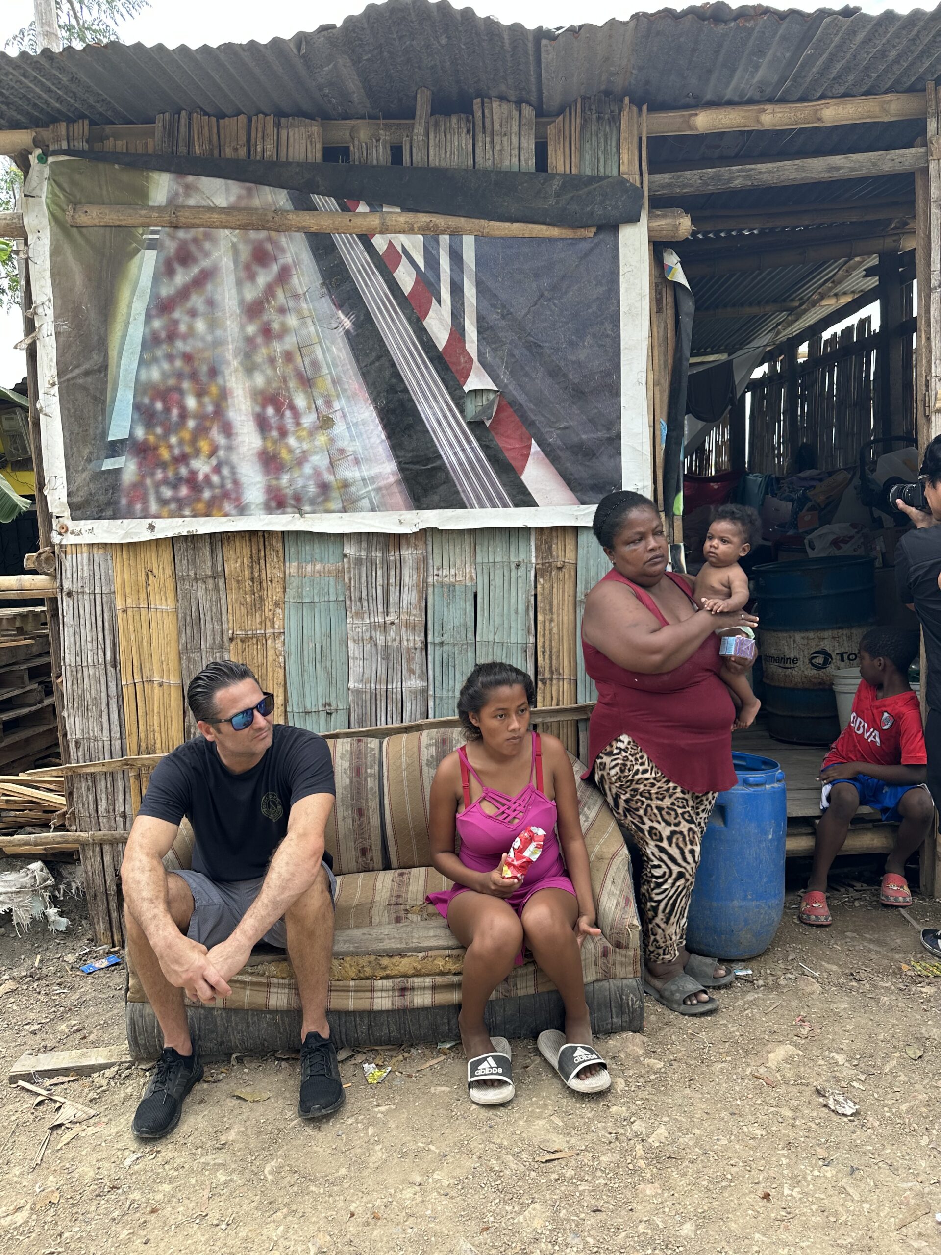 U4O volunteer sits outside of building with Ecuadorian children and adults